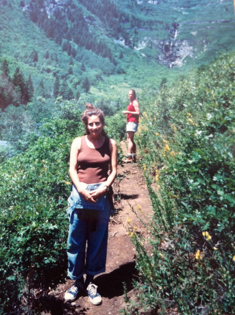 一个女人站在山区的一条小径上的前景中。