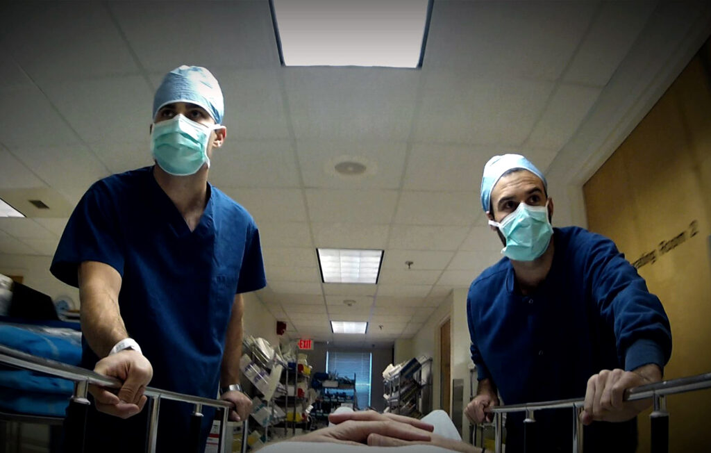 两个ER医学专家在蓝色口罩用担架床冲进急诊室。