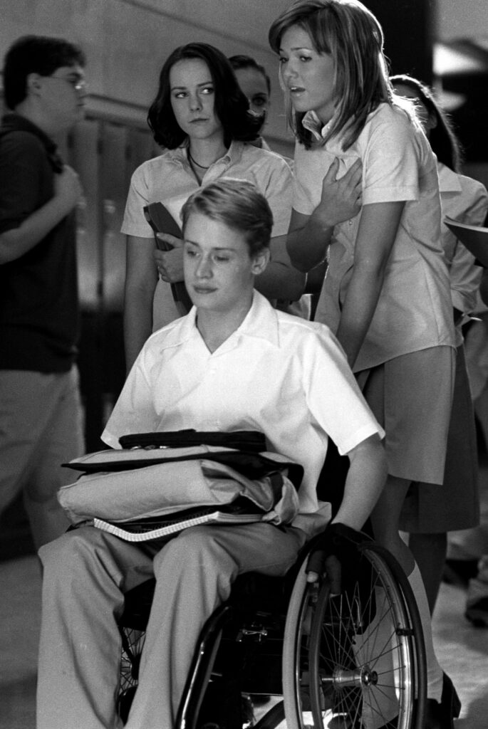 年轻人坐在轮椅上,身后的两个年轻女人