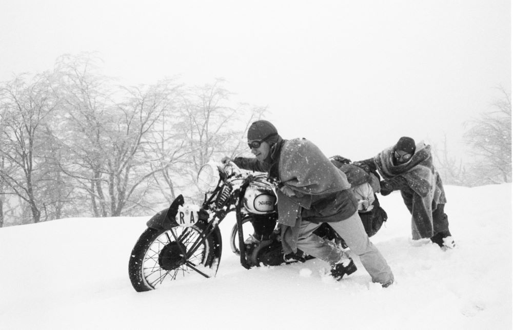 两个人推着一辆摩托车穿过雪地