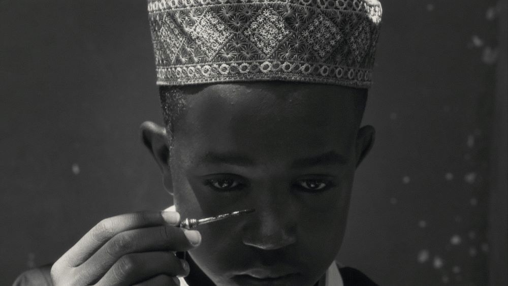 年轻的黑人戴着装饰性的部落帽，把颜料涂在脸上