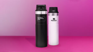 两个水瓶——一个黑一个白——站在粉红色的背景前面