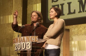 一个男人和一个女人站在一个讲台上，上面写着:圣丹斯2003”