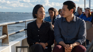 年轻的亚洲女人和男人并肩坐着看着对方,别人也在船上运输。